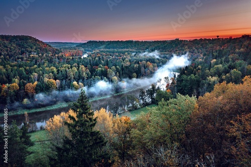 Obraz na płótnie Colorful sunrise over the Gauja National park valley. Sigulda city panorama from drone with forest in autumn colors. w salonie