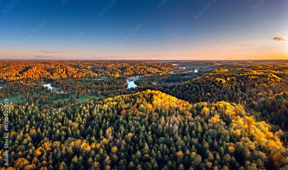 Colorful sunrise over the Gauja National park valley. Sigulda city panorama from drone with forest in autumn colors.