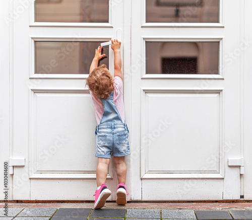 Obraz na płótnie The child tries to open the door. The child reaches for the doorknob on the street. w salonie
