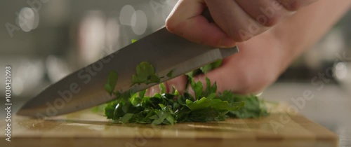 Close-up of a chef cutting a green with a knife on a wooden board. Slicing a green with a knife. Cutting vegetables, Culinary show cinematic footage slow motion