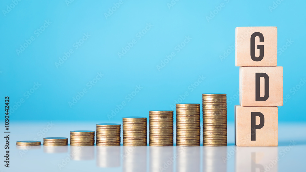 A wooden block labeled 'GDP' next to a stack of coins arranged from smallest to largest. Concept of economic growth and the role of Gross Domestic Product in measuring a country's financial progress A wooden block labeled 'GDP' next to a stack of coins arranged from smallest to largest. Concept of economic growth and the role of Gross Domestic Product in measuring a country's financial progress