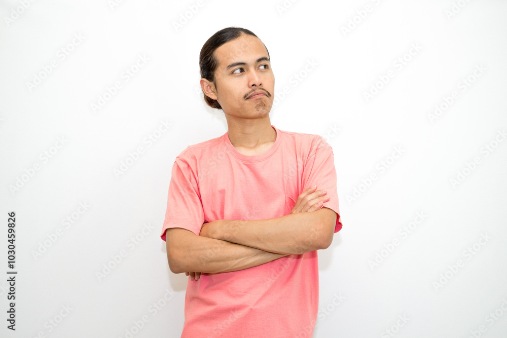 An Indonesian, Asian man wearing a pink tshirt shows a fierce expression as if he is angry or frustrated. isolated in white background An Indonesian, Asian man wearing a pink tshirt shows a fierce expression as if he is angry or frustrated. isolated in white background