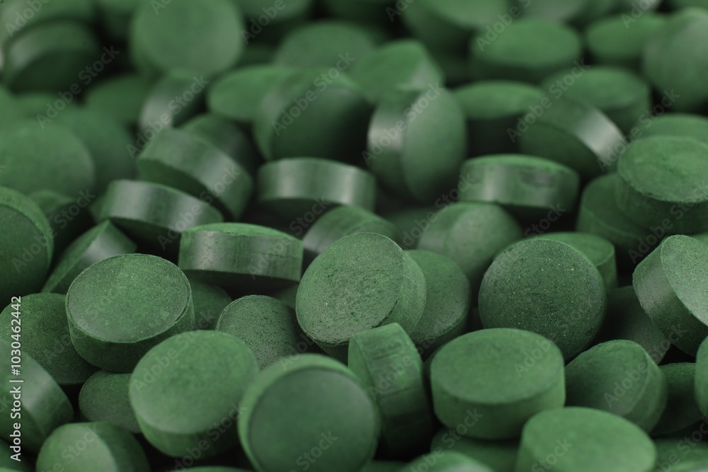 Green spirulina tablets arranged closely on a surface in natural light Green spirulina tablets arranged closely on a surface in natural light