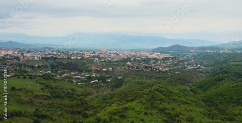 A panoramic view of Nagorno Karabakh featuring lush green hills and distant mountains under a cloudy sky photo