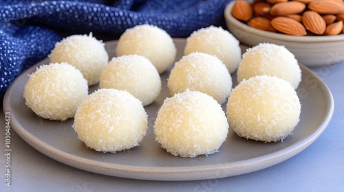 A beautifully arranged plate features chocolate-covered deer balls topped with shredded coconut, complemented by wooden bowls filled with more coconut, all on a gray backdrop.