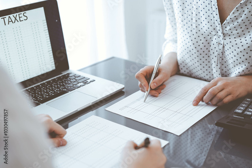 Two accountants use a laptop computer for counting taxes or revenue balance. Business, audit, and taxes concepts photo