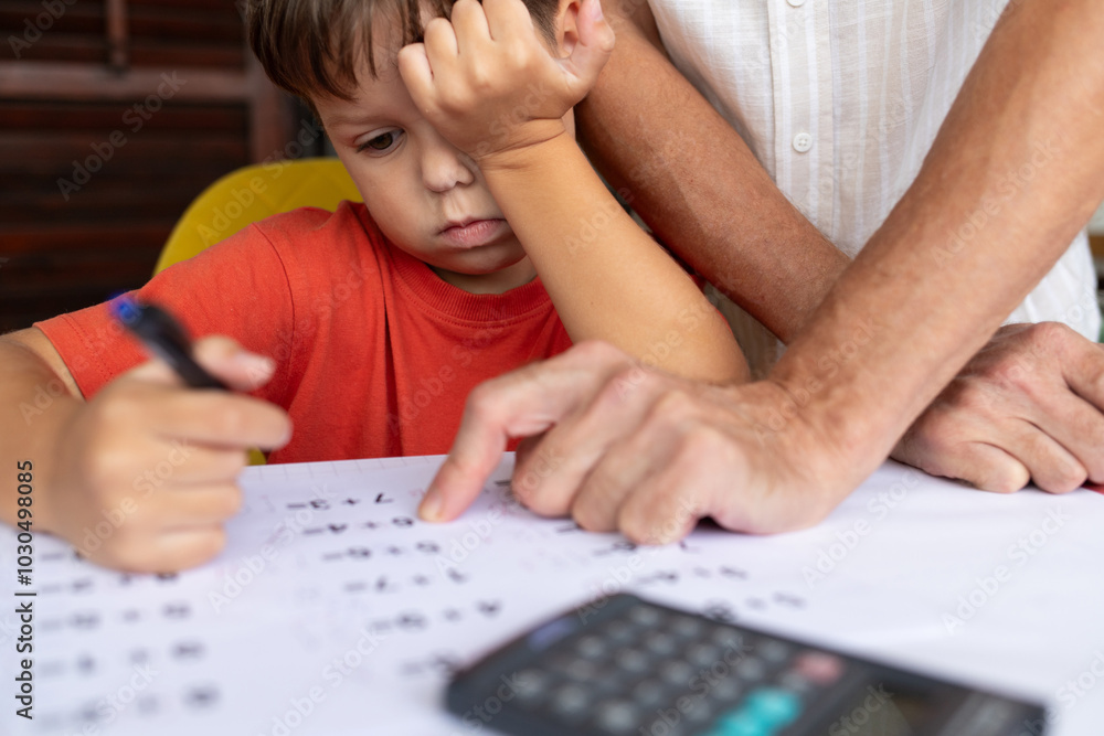 Fototapeta premium A father helps his 6-year-old son with his math homework.