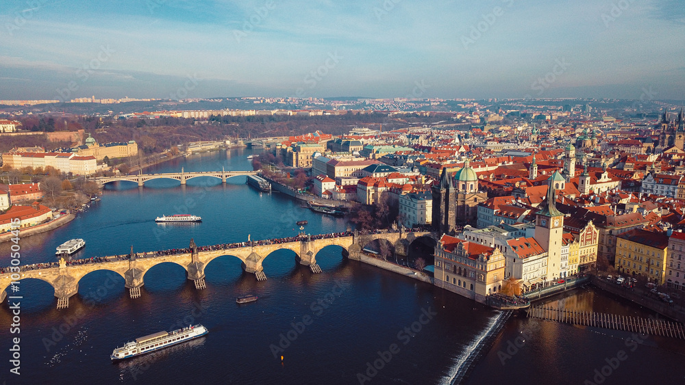 Fototapeta premium Aerial view of Prague showcasing historic bridges, colorful rooftops, and the Vltava River during a clear day