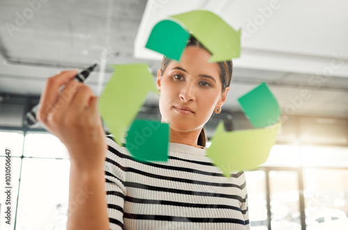 Business, woman and strategy with recycle logo on glass wall for eco friendly, environment or ecology. Female person, employee and serious with brainstorming or planning for green or sustainability photo