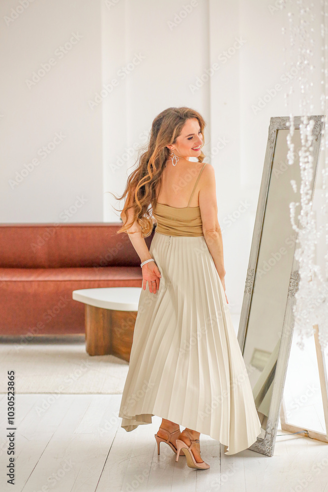 A beautiful Caucasian girl dancing near a mirror in a beige top and a milk-colored maxi skirt. Sensuality and sexuality. Women. Great mood concept A beautiful Caucasian girl dancing near a mirror in a beige top and a milk-colored maxi skirt. Sensuality and sexuality. Women. Great mood concept
