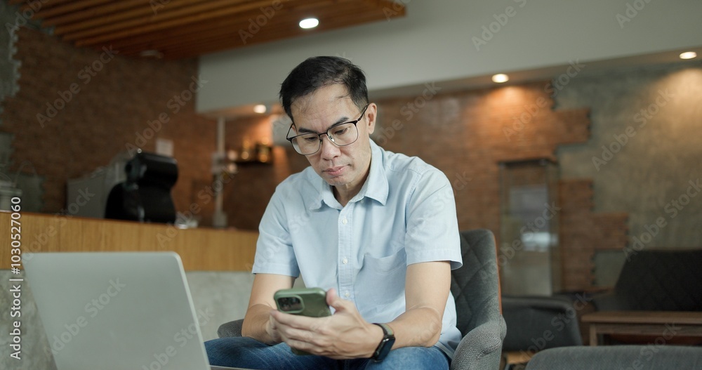 Businessman chatting on laptop. communication technology. Asian Middle-aged man using smartphone to shop online. Senior make financial transactions, transfer money via bank apps, order products. Businessman chatting on laptop. communication technology. Asian Middle-aged man using smartphone to shop online. Senior make financial transactions, transfer money via bank apps, order products.