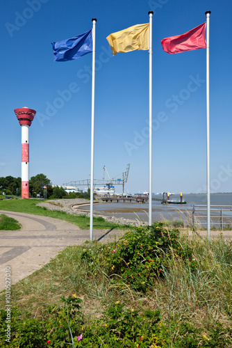 Nordenham, lighthouse and harbor on the Weser river, flagpoles in foreground photo