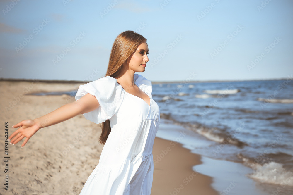 Happy smiling beautiful woman is on the ocean beach in a white summer dress, open arms Happy smiling beautiful woman is on the ocean beach in a white summer dress, open arms