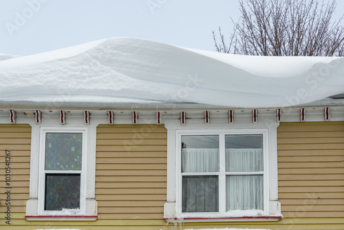 фотографія Thick white snow drifts on the top roof of a yellow wooden house
