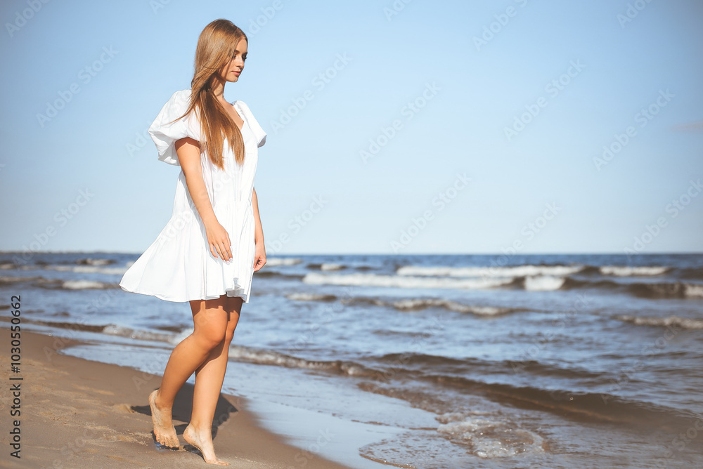 Happy smiling beautiful woman is walking on the ocean beach in a white summer dress Happy smiling beautiful woman is walking on the ocean beach in a white summer dress