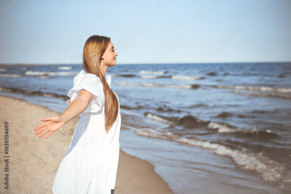 Happy, beautiful woman on the ocean beach standing in a white summer dress, open arms Happy, beautiful woman on the ocean beach standing in a white summer dress, open arms