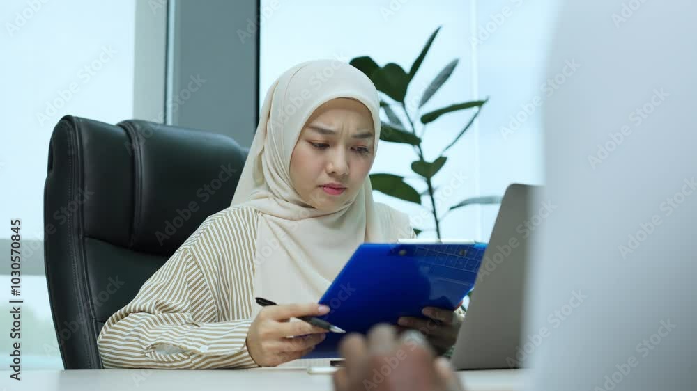 Worried businesswoman in a hijab reviews documents in an office, reflecting stress and job insecurity, possibly facing job-related challenges. Worried businesswoman in a hijab reviews documents in an office, reflecting stress and job insecurity, possibly facing job-related challenges.