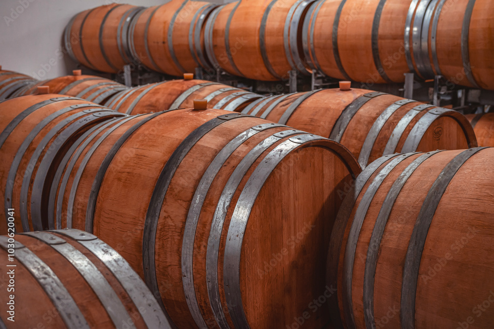 Wooden barrels stacked in wine cellar, showcasing the craft of aging fine wines in a rustic setting Wooden barrels stacked in wine cellar, showcasing the craft of aging fine wines in a rustic setting