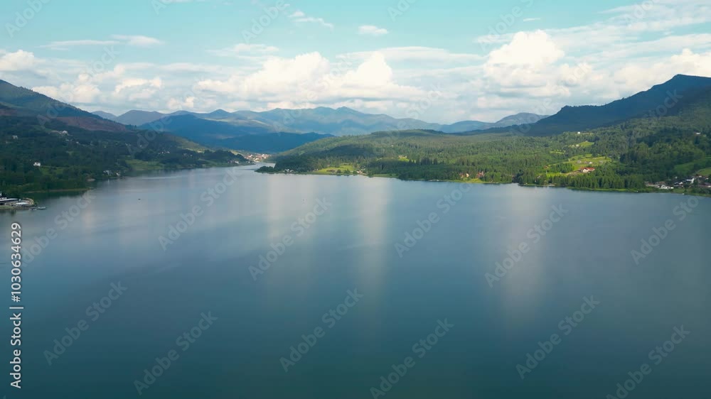 Aerial perspective of Colibita Lake, Romania. Colibita is an artificial accumulation lake on the Călimani mountains, county Bistriţa-Năsăud. Green landscape. Forest. Drone panning right. Travel. Aerial perspective of Colibita Lake, Romania. Colibita is an artificial accumulation lake on the Călimani mountains, county Bistriţa-Năsăud. Green landscape. Forest. Drone panning right. Travel.