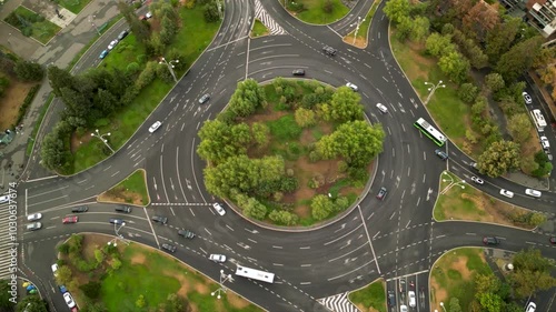 High angle drone footage of Herastrau and Piata aviatorilor Bucharest Romania. Green roundabout seen on a sunny day during golden hour. Traffic navigating a rotary intersection. Flowing traffic.
 photo