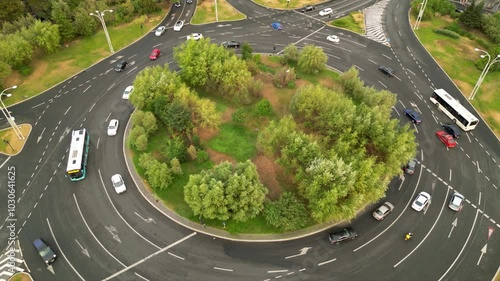 High angle drone footage of Herastrau and Piata aviatorilor Bucharest Romania. Green roundabout seen on a sunny day during golden hour. Traffic navigating a rotary intersection. Flowing traffic.
 photo