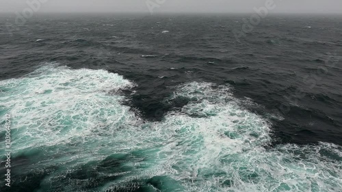 Ocean waves and light rain was viewed from a ship while traveling in the Pacific Northwest off the coast of Alaska