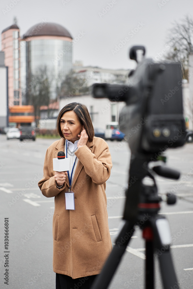 Fototapeta premium A female journalist readies her microphone to report in a busy city, embodying resilience.