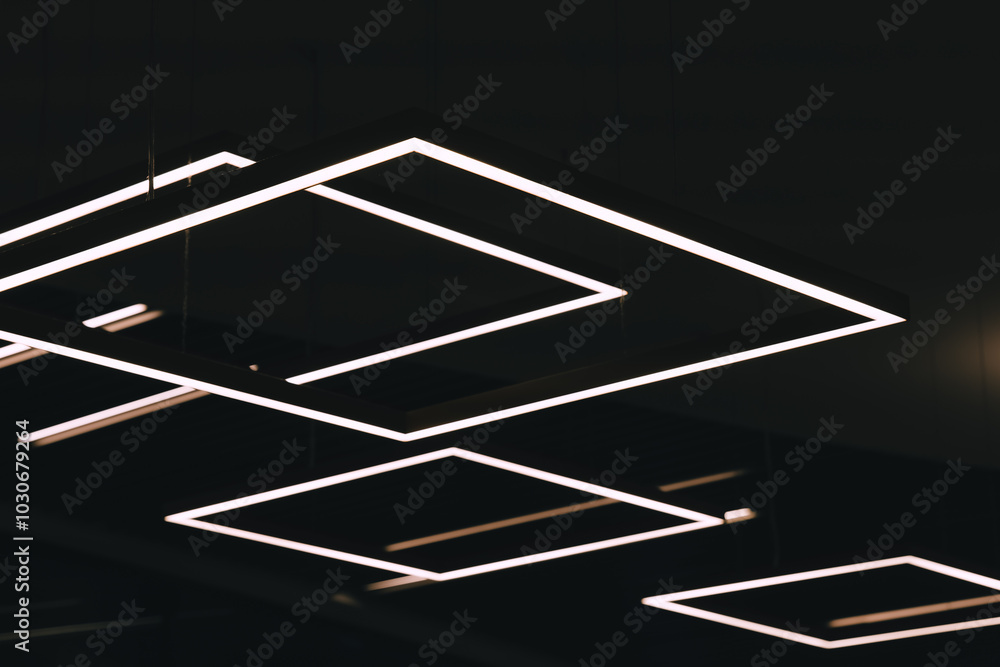 Geometric light fixtures illuminate the ceiling of a modern building Geometric light fixtures illuminate the ceiling of a modern building