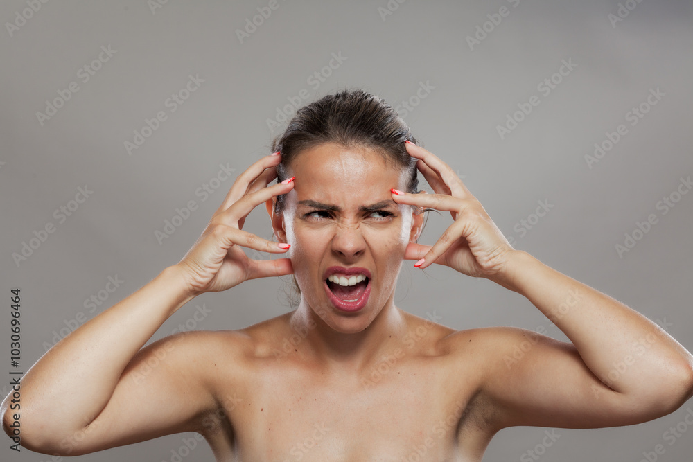 Fototapeta premium Young woman in distress with hands on temples showing strong emotions