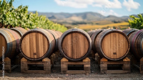 Neatly stacked wooden barrels in a vineyard, with a backdrop of rolling hills and a vibrant, sunny sky, capturing the essence of winemaking.