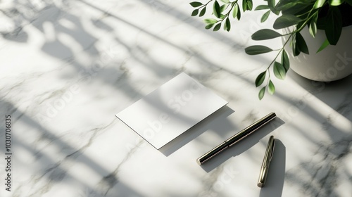 Blank white card and pen on marble table with natural light and plant shadow. photo