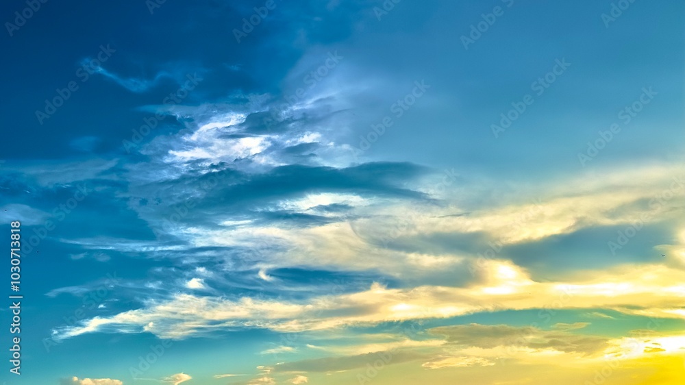 Fototapeta premium Two-tone sky photo with beautiful clouds in shape, light orange and blue sky background, white clouds reflecting the evening sunlight.