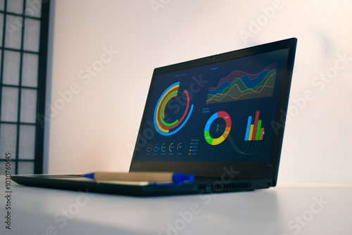 Laptop on a white table, with chart concepts on the screen photo