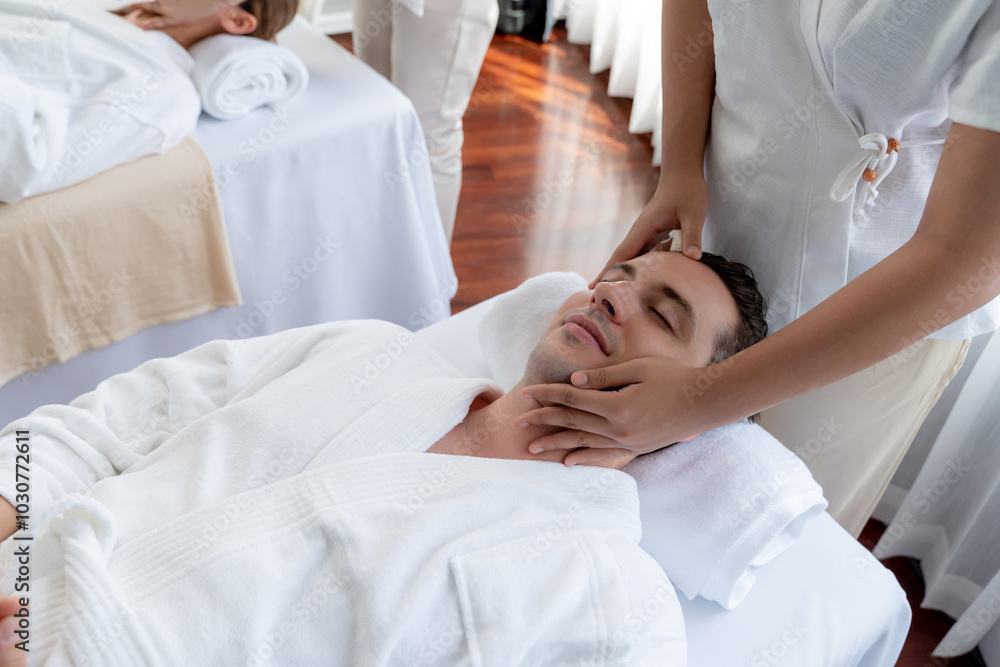 Caucasian couple enjoying relaxing anti-stress head massage and pampering facial beauty skin recreation leisure in dayspa modern light ambient at luxury resort or hotel spa salon. Quiescent Caucasian couple enjoying relaxing anti-stress head massage and pampering facial beauty skin recreation leisure in dayspa modern light ambient at luxury resort or hotel spa salon. Quiescent