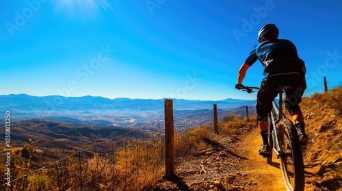 Mountain biker riding on a scenic trail under a bright blue sky.