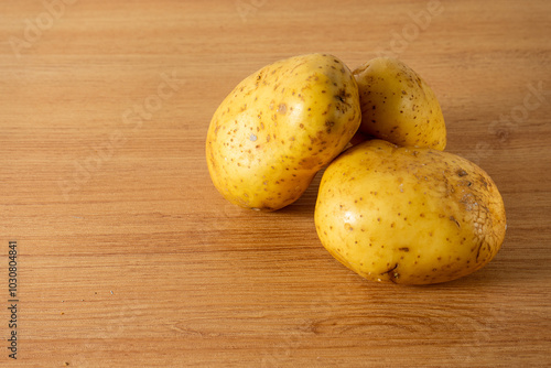 raw white potatoes scattered on a clean kitchen countertop, ready for cooking. Natural light enhances the smooth texture and earthy tones of the potatoes. photo