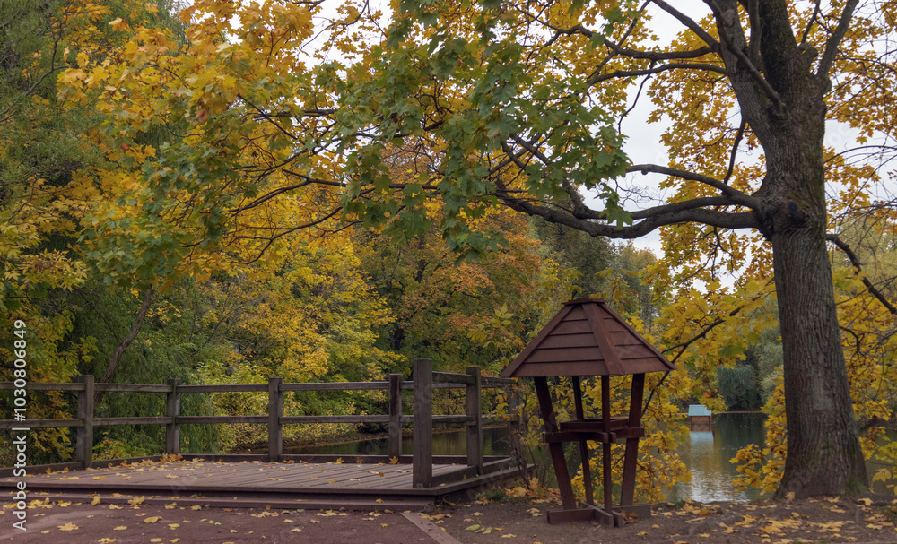 A tranquil autumn setting featuring a wooden deck over a calm body of water, adorned with vibrant yellow-orange leaves and a rustic lantern, embodying the peace of nature. A tranquil autumn setting featuring a wooden deck over a calm body of water, adorned with vibrant yellow-orange leaves and a rustic lantern, embodying the peace of nature.