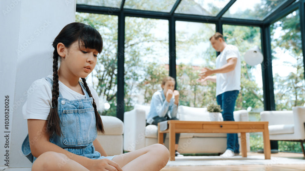 Stressed and unhappy young girl huddle in corner, cover her ears blocking sound of her parent arguing in background. Domestic violence at home and traumatic childhood develop to depression. Synchronos Stressed and unhappy young girl huddle in corner, cover her ears blocking sound of her parent arguing in background. Domestic violence at home and traumatic childhood develop to depression. Synchronos