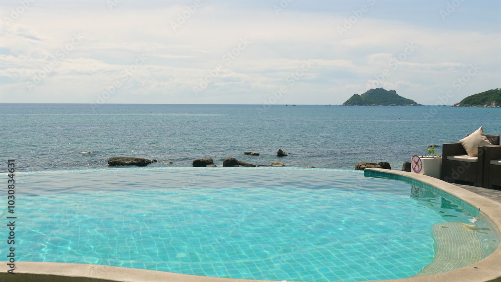 Scenic view of infinity pool overlooking serene ocean and distant island on sunny day. Relaxation and Tranquility. Scenic view of infinity pool overlooking serene ocean and distant island on sunny day. Relaxation and Tranquility.