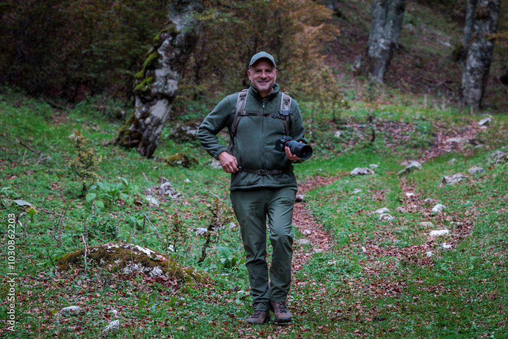 Hiker explores the trail in the beech forest in search of interesting subjects to photograph in the autumn season. Hiker explores the trail in the beech forest in search of interesting subjects to photograph in the autumn season.
