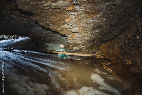 In a dimly lit cave, a person stands firmly grasping a sturdy wooden stick, indicating they might be exploring or preparing for an adventure within the caves mysterious depths photo