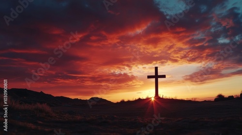 Silhouette of a cross against a dramatic sunset sky in an open landscape