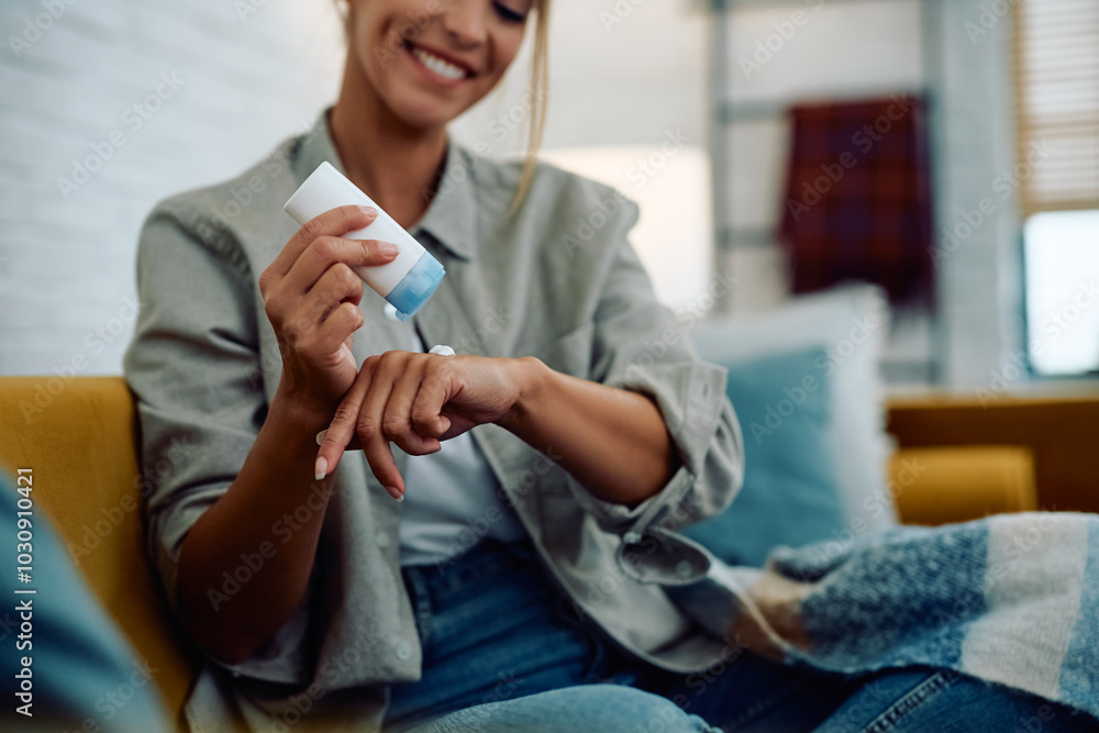 Fototapeta premium Close up of woman applying hand cream at home.