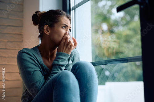 Ill woman blowing nose by window. Free Download Ill woman blowing nose by window. - GFXLoad