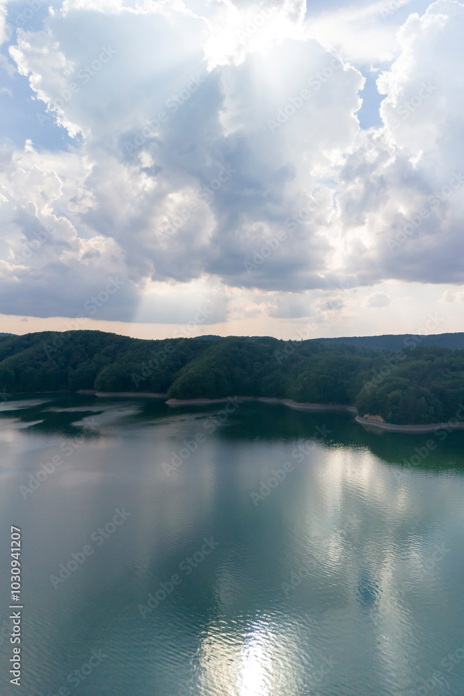 Stunning aerial view showcasing serene waters reflecting clouds and sunlight, surrounded by lush greenery. Stunning aerial view showcasing serene waters reflecting clouds and sunlight, surrounded by lush greenery.