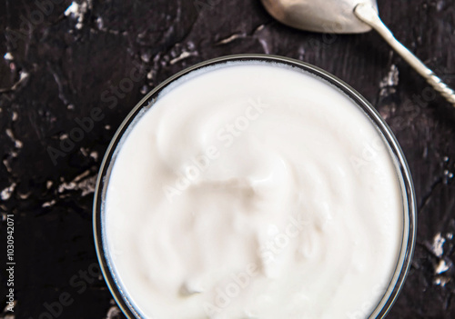 Bowl of tasty fresh sour cream on a dark background