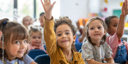 A group of happy children sitting at desks in an elementary school classroom, raising their hands and rushing for the teacher's attention.