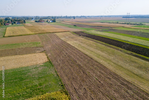 Aerial view of vibrant agricultural fields displaying a patchwork of green, brown, and yellow hues under a clear blue sky. Ideal for nature and landscape themes. photo