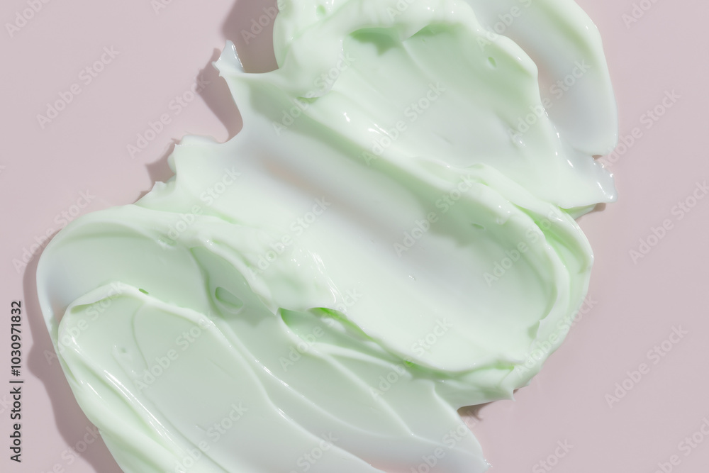 Green beauty cream smear smudge on pink background. Cosmetic skincare product texture. Face cream, body lotion swipe swatch Green beauty cream smear smudge on pink background. Cosmetic skincare product texture. Face cream, body lotion swipe swatch