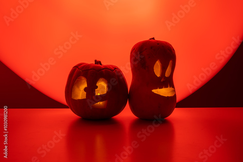 Two jack-o-lanterns glow in the dark on a red background. Halloween decoration. photo